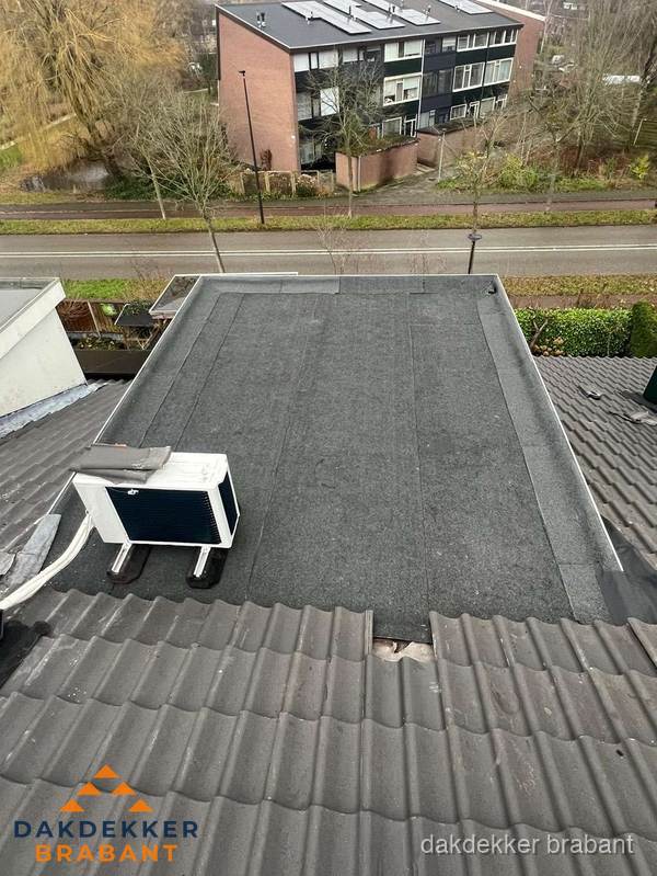 Plat dak inspectie met bitumen bedekking naast schuin pannendak in Brabant