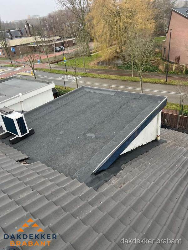 Plat dak met bitumen dakbedekking naast schuin pannendak in Brabant