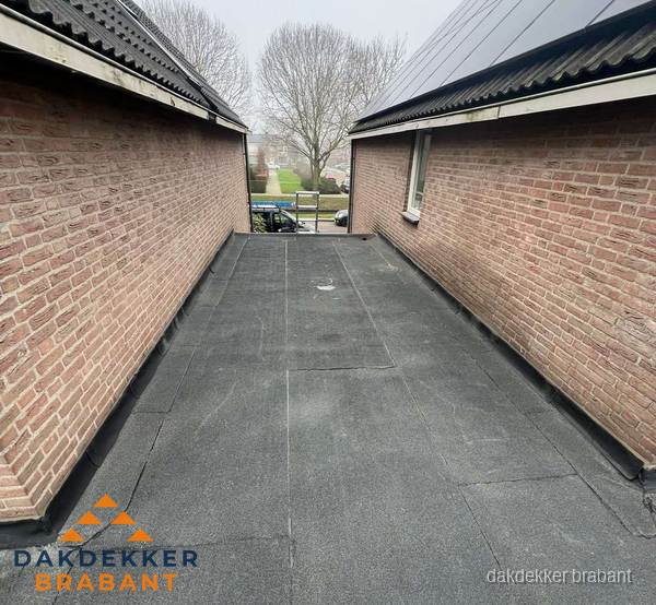 Plat dak met bitumen dakbedekking tussen bakstenen muren in Brabant