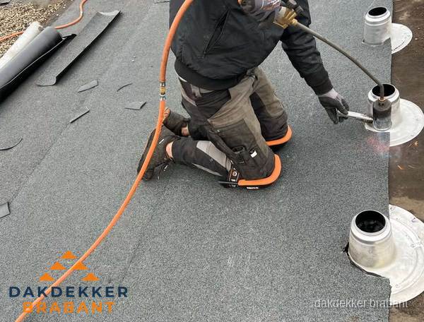 Dakdekker repareert bitumen dakleer bij dakdoorvoer in Brabant