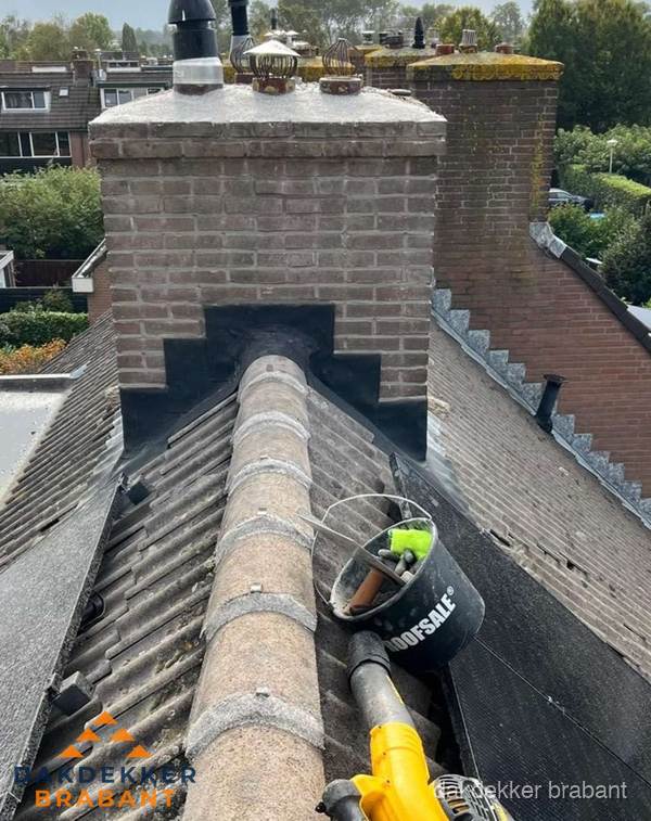 Schoorsteen met loodaansluiting en nokvorst op pannendak in Brabant