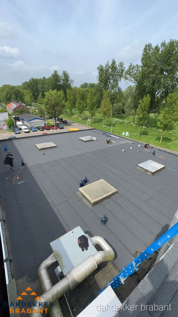 Dakdekker aan het werk op groot plat dak met bitumen in Brabant